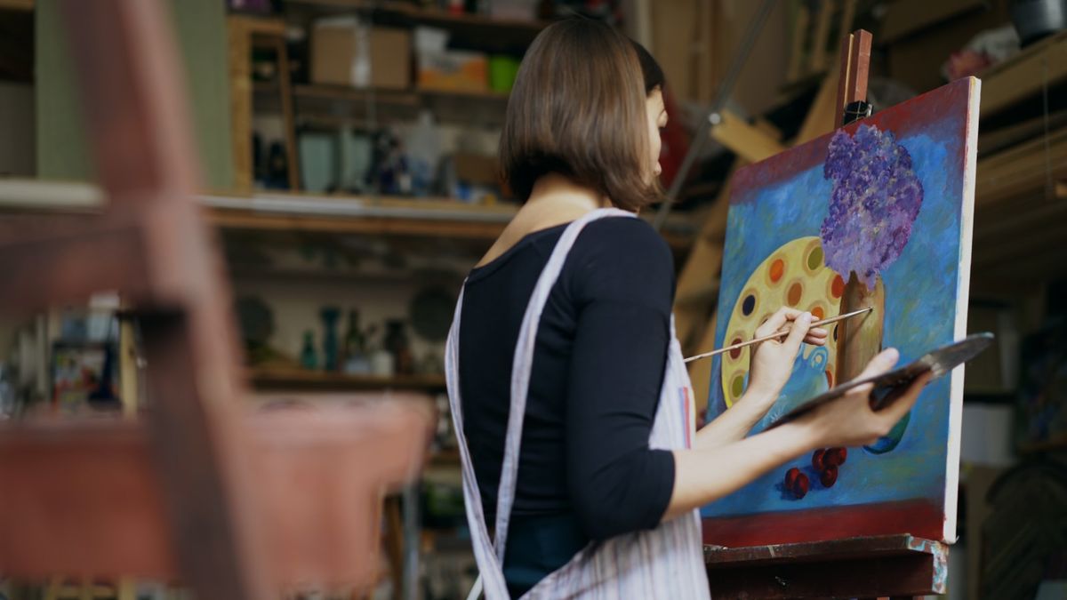 Kunstner maler bilde ved staffeli i atelier