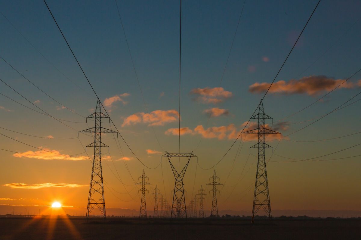 Hoyspentmaster og kraftlinjer i solnedgang