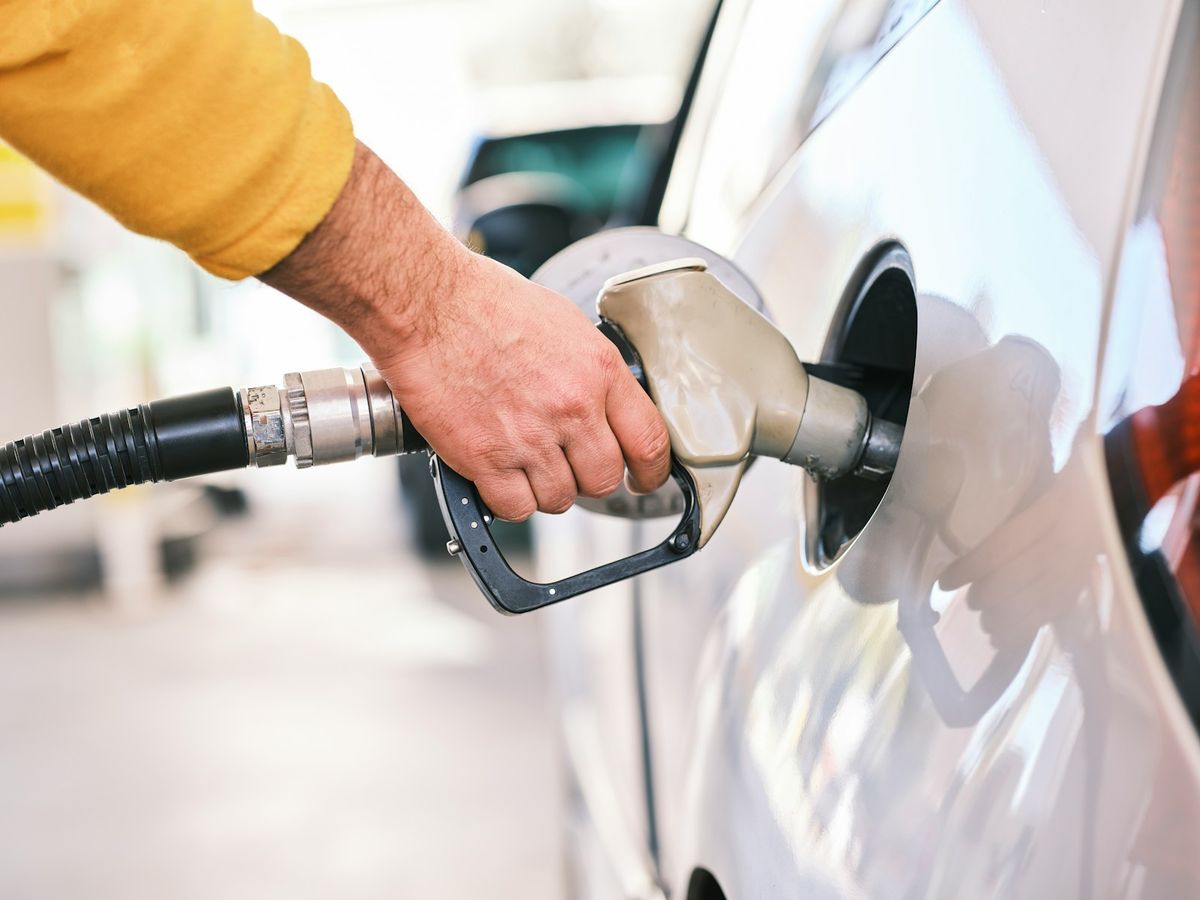 Person fyller drivstoff pa bil ved bensinstasjon