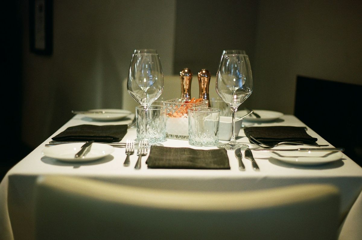 Dekket restaurantbord med vinglass og bestikk