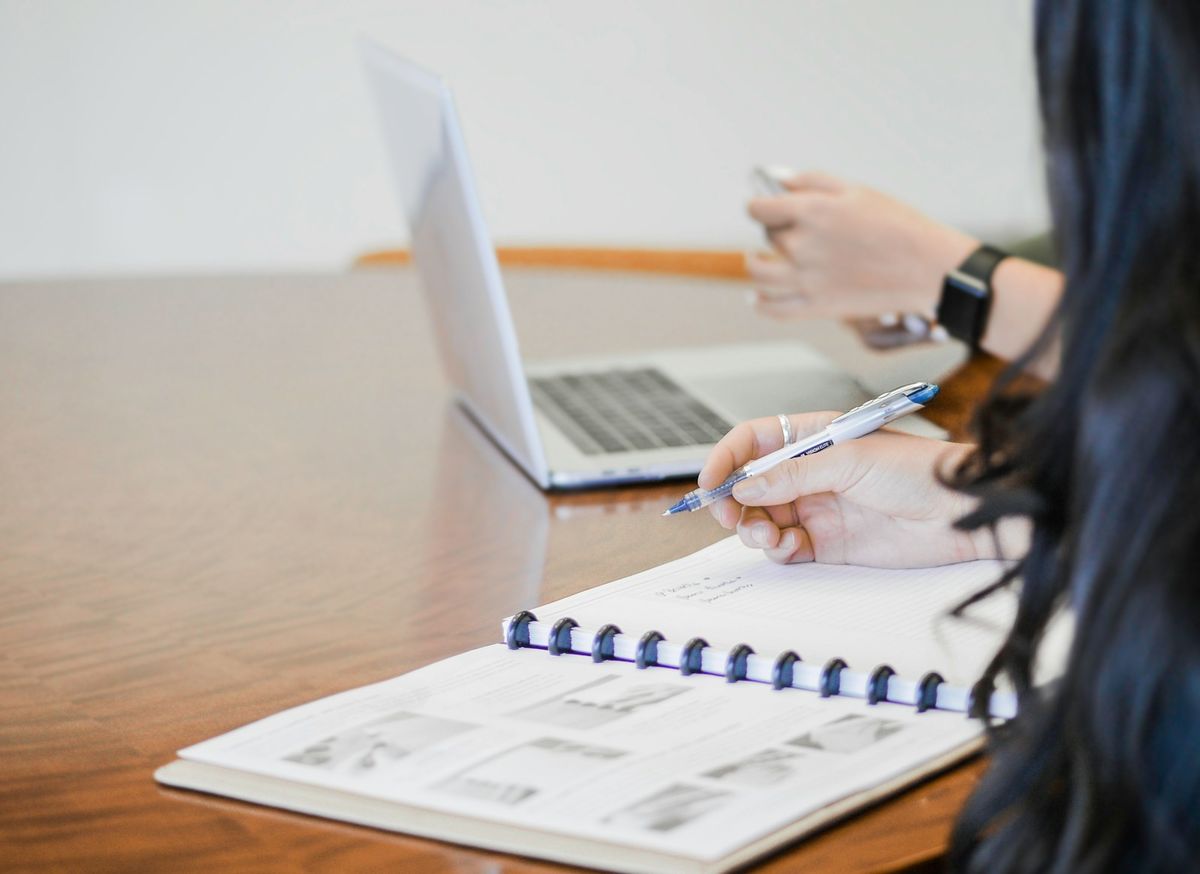 Person fyller ut dokument med penn ved skrivebord