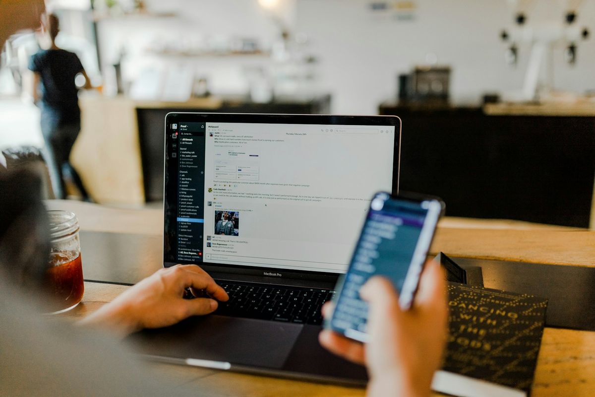 Person jobber med laptop og mobil på kontor