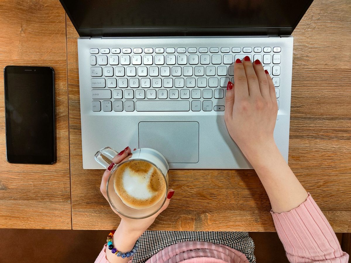 Person fyller ut skjema paa laptop ved skrivebord