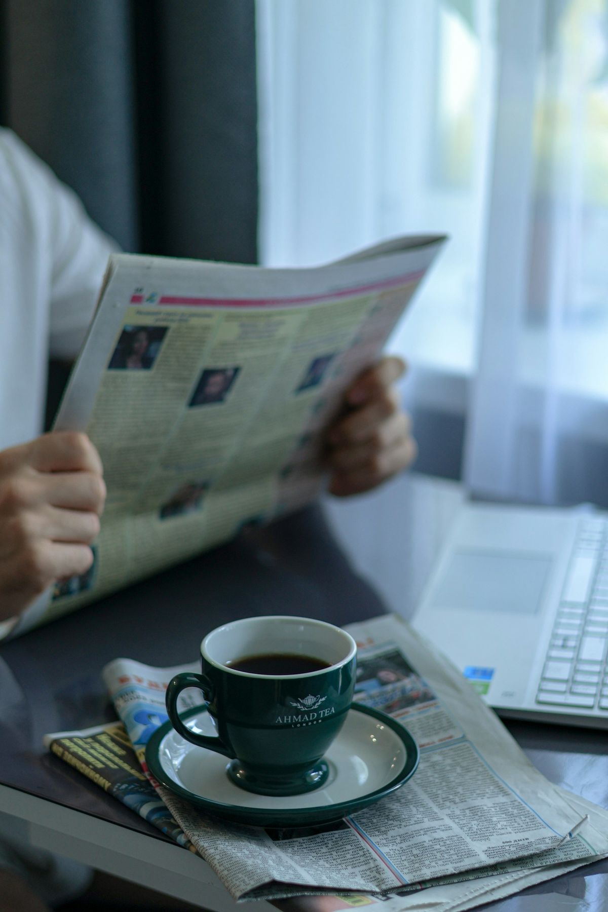 Person leser avis med nyheter og drikker kaffe