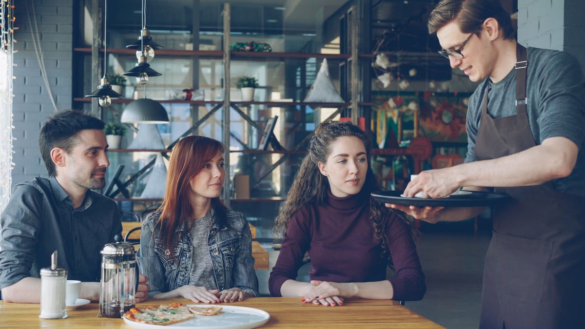 Servitør serverer mat til et par på restaurant