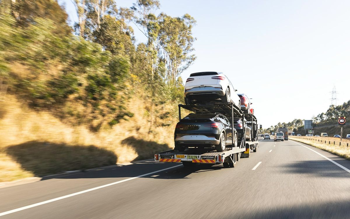 Biltransporter kjorer med biler langs motorvei
